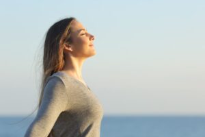 A woman is standing in the sunlight near water.